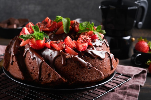 Torta bundt al cioccolato fondente con glassa di ganache e fragola su pietra scura o sfondo del tavolo in cemento torta festiva messa a fuoco selettiva