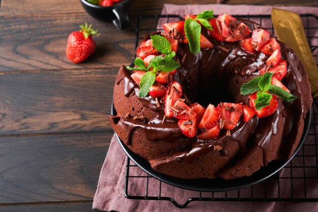 Dark Chocolate Bundt Cake with Ganache Icing and strawberry on dark stone or concrete table background Festive cake Selective focus