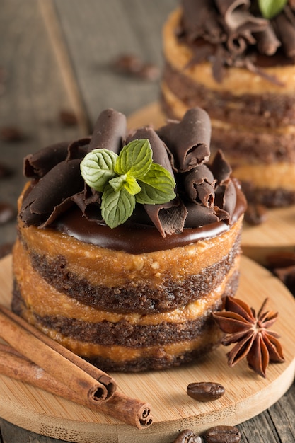 Dark chocolate cakes on black slattern board with mint, cinnamon, coffee beans on a wooden  background. Tasty dessert food concept.