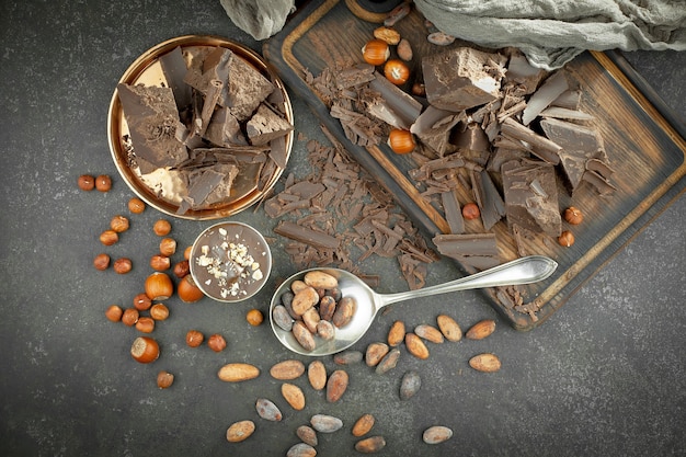 Photo dark chocolate in a composition with cocoa beans and nuts, on an old background.