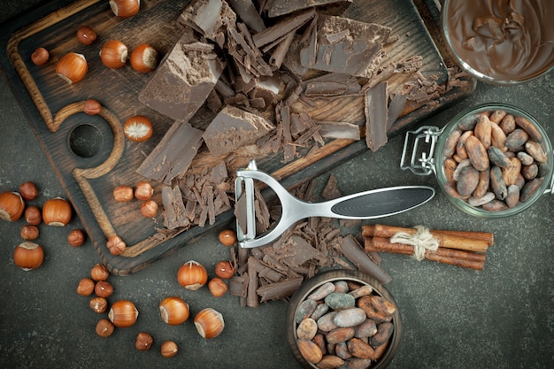 Photo dark chocolate in a composition with cocoa beans and nuts, on an old background.