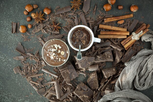 Dark chocolate in a composition with cocoa beans and nuts, on an old background.