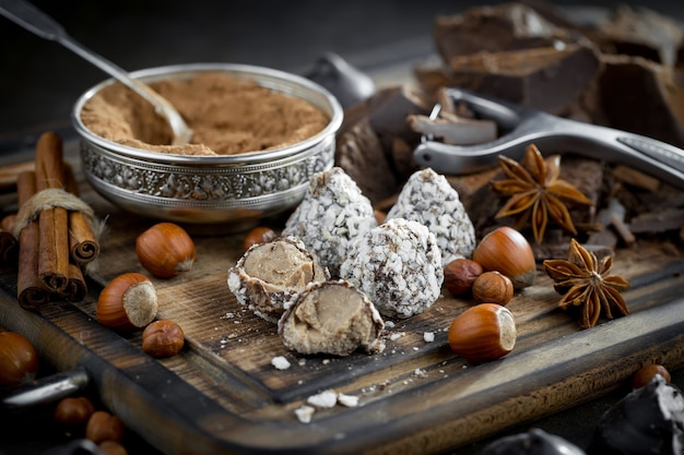 Dark chocolate in a composition with cocoa beans and nuts, on an old background.