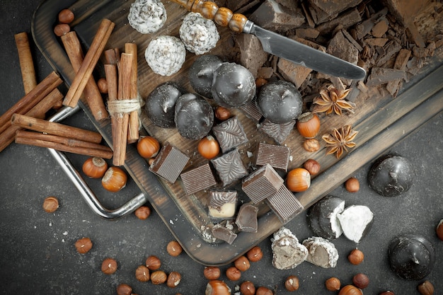 Темный шоколад в композиции с какао-бобами и орехами, на старом фоне.