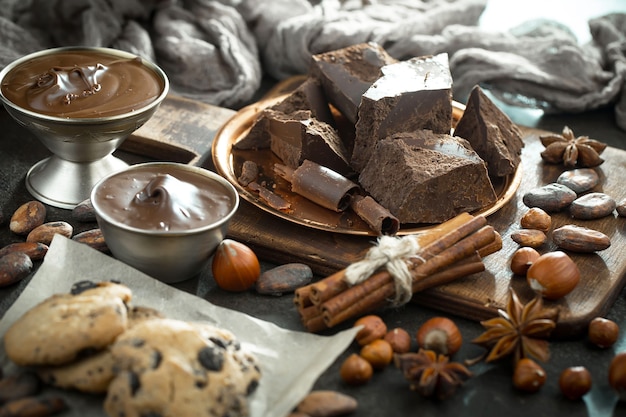 Dark chocolate in a composition with cocoa beans and nuts, on an old background.