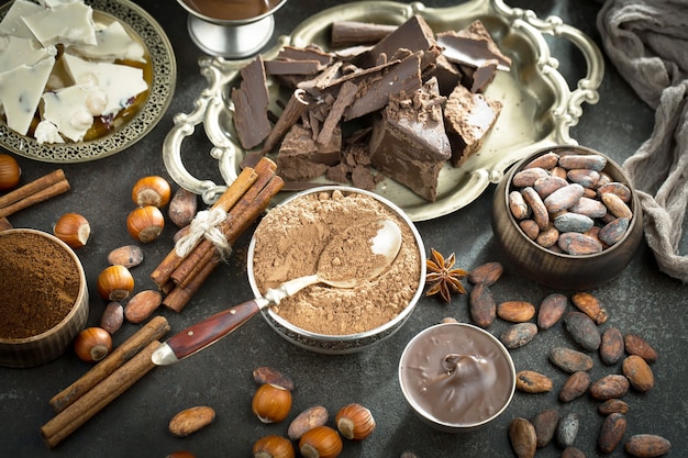 Dark chocolate in a composition with cocoa beans and nuts, on an old background.