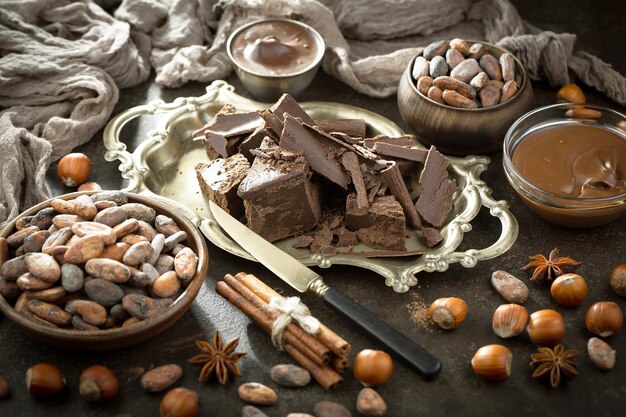 Cioccolato fondente in una composizione con fave di cacao e noci, su un vecchio sfondo.