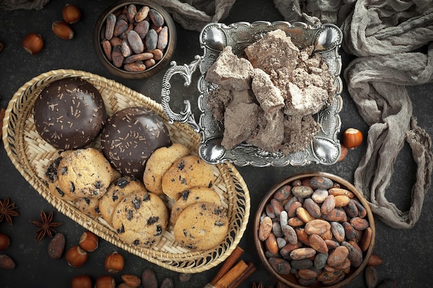 Dark chocolate in a composition with cocoa beans and nuts, on an old background.