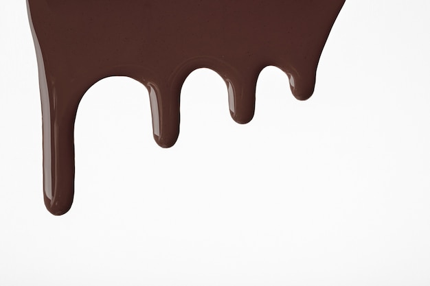 Dark chocolate liquid drops of paint flow down on isolated white background