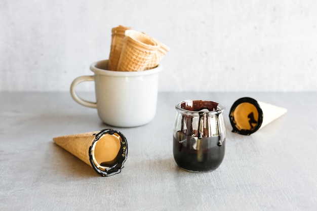 Salsa di cioccolato fondente vicino alla tazza di coni di gelato