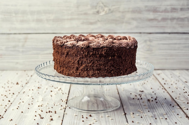 나무 배경에 사탕과 크림을 넣은 다크 초콜릿 비건 케이크