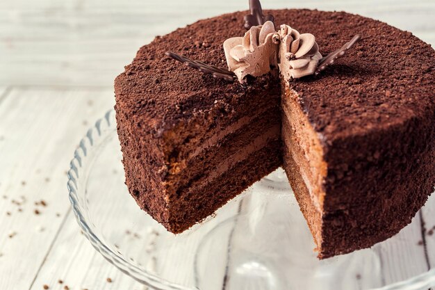 Dark chocolate vegan cake with candies and cream on wooden background