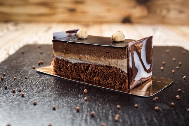 Dark chocolate vegan cake with candies and nuts on wooden background