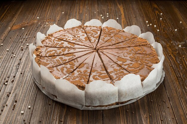 Dark chocolate vegan cake with candies and nuts on wooden background