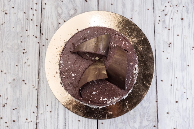 Dark chocolate vegan cake with candies and nuts on wooden
background