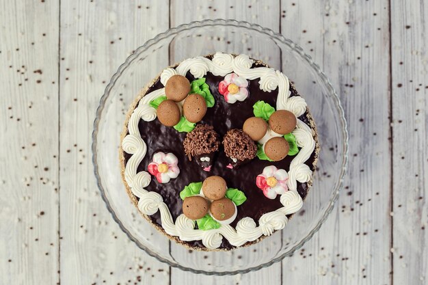 Dark chocolate vegan cake with cream and caramel on wooden background