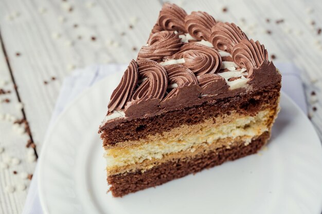 Dark chocolate vegan cake with cream and caramel on wooden background