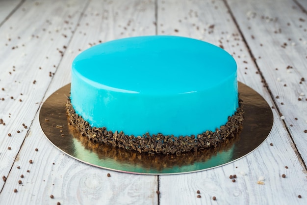 Dark chocolate vegan cake with cream and fruit mirror glaze on\
wooden background