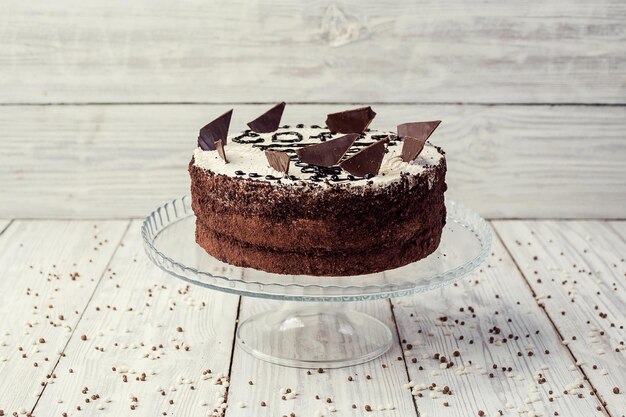 Dark chocolate vegan cake with cream on wooden background