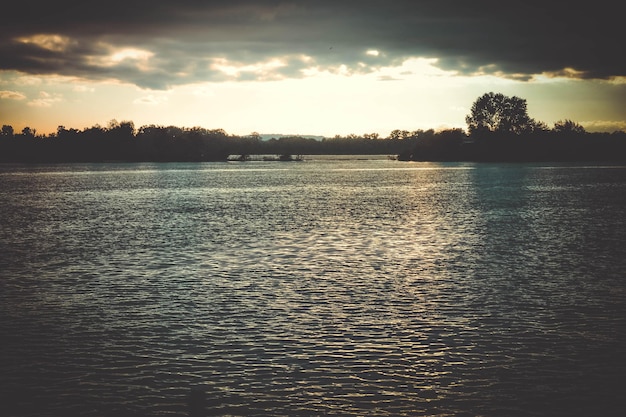 Dark clouds at sunset sunrise above water surface