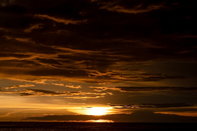 Dark cloudy golden sunset sky on the sea