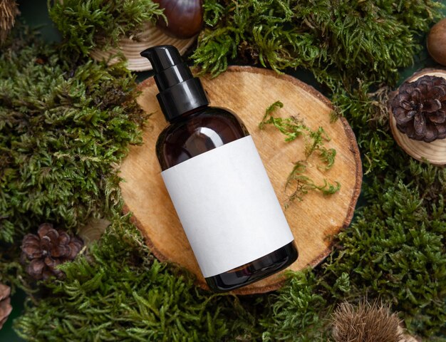 Bottiglia cosmetica scura con etichetta vuota su pezzo di legno tra mockup vista dall'alto di muschio verde