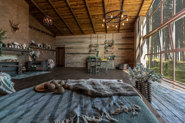 Dark cozy interior of big country wooden house, wooden furniture and animal furs. huge panoramic window and very high ceiling.