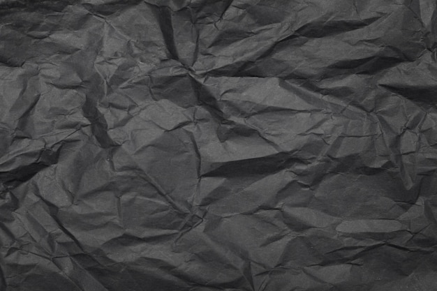 Dark crumpled sheet of paper. Old gray wallpaper background