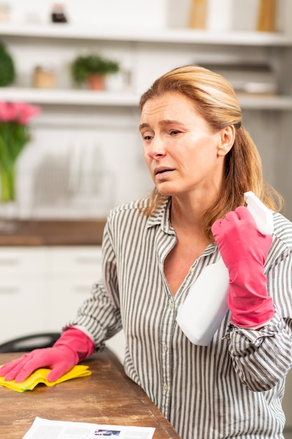 Dark eyed mature woman feeling really sick cleaning apartment while having allergy