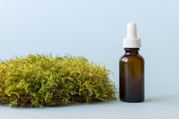 Dark glass bottle with dropper with moss decoration