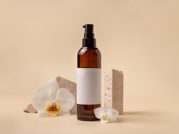 Dark glass cosmetic bottle near white orchid flowers and stones on light yellow close up Mockup