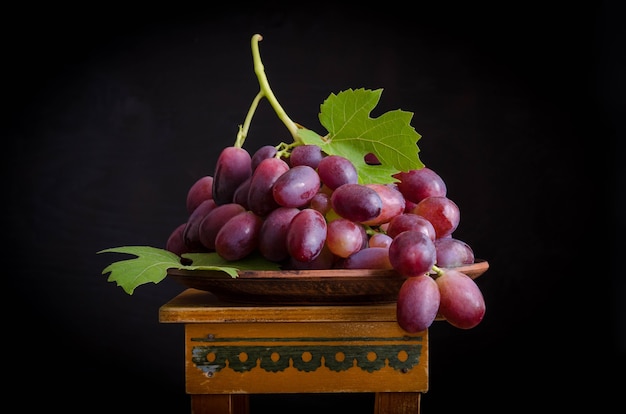 Dark grapes on a wooden plate