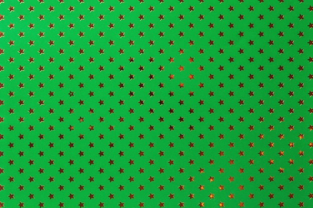 金色の星のパターンを持つ金属箔紙から濃い緑色の背景。