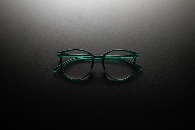 Dark green eyewear with dark background and dramatic shadow effect