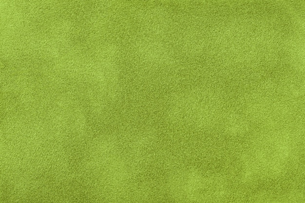 Dark green matte background of suede fabric, closeup. Velvet texture of seamless olive textile, macro. Structure of khaki felt canvas backdrop.