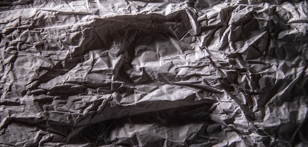 Dark grey crumpled paper texture.