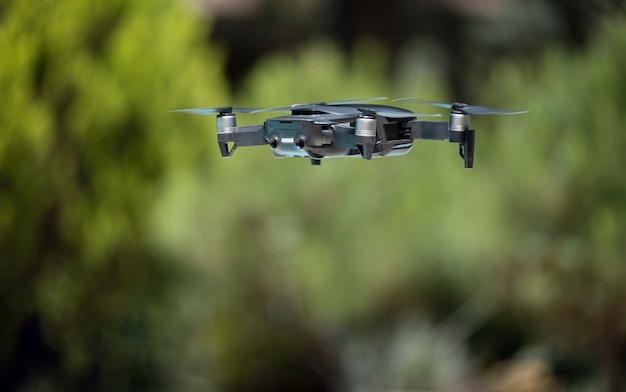 Dark grey drone flying over a green background