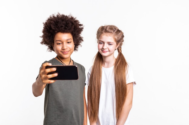 Dark-haired boy. Pretty young kids making selfie together on smartphone while standing closely in studio