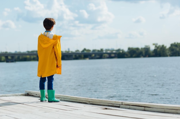 Dark-haired boy wearing yellow raincoat and wellingtons