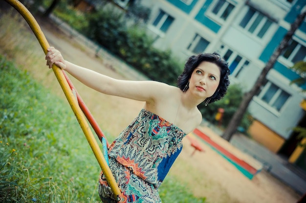 Dark-haired girl in a long colorful summer dress in nature