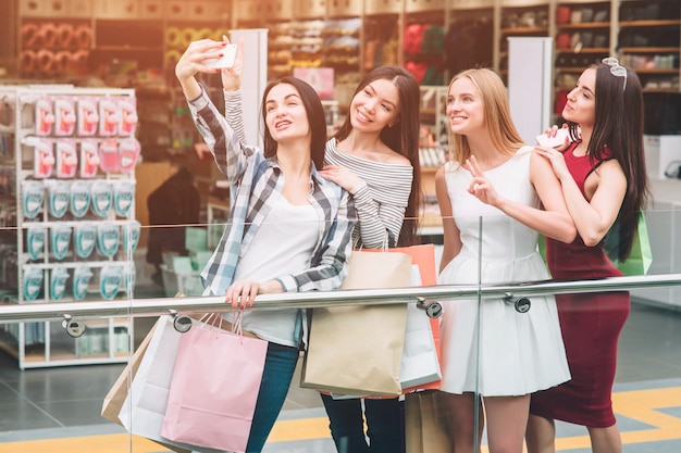 Ragazza dai capelli scuri in pantaloni si sta fotografando con gli amici