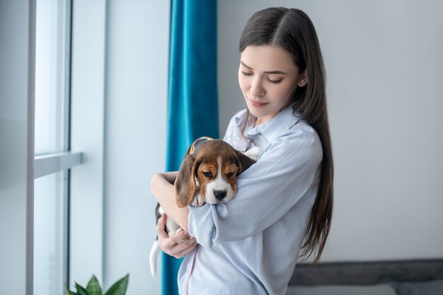 Dark-haired girl with her puppy at home feeling peaceful