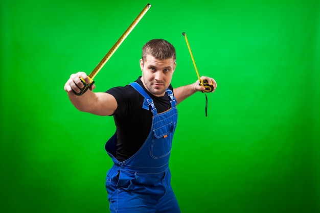 Photo a dark-haired man builder in a black t-shirt and blue construction jumpsuit