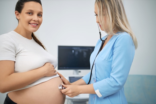 Donna incinta dai capelli scuri che riceve cure mediche professionali da una dottoressa