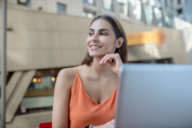 Dark-haired pretty woman sitting at the laptop and looking aside