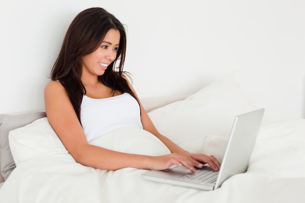 dark-haired woman with notebook lying in bed