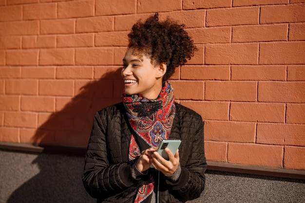 Dark-haired young girl in jacket with a phone in hands