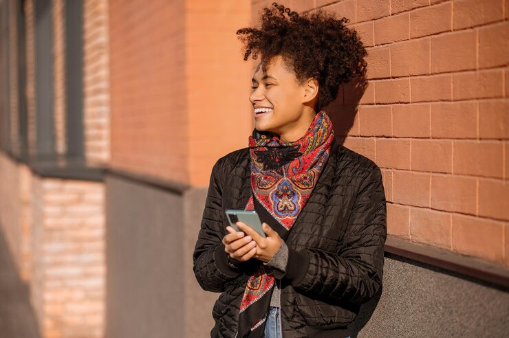 Dark-haired young girl in jacket with a phone in hands