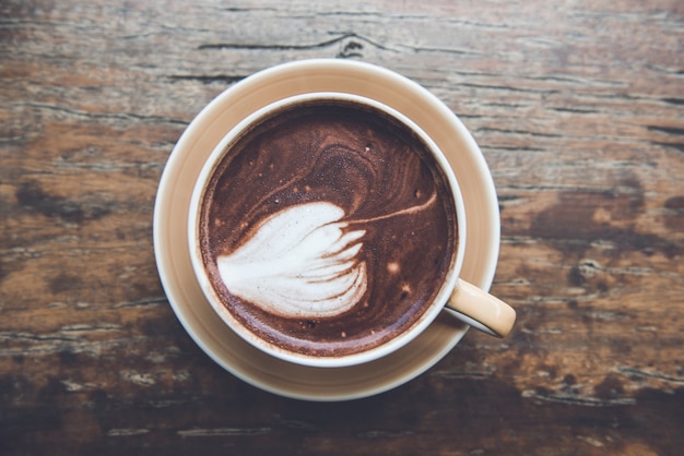 Dark hot chocolate beverage in the cup on old wood table background