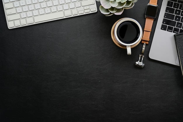 Photo dark leather desk with home office gadget and copy space.